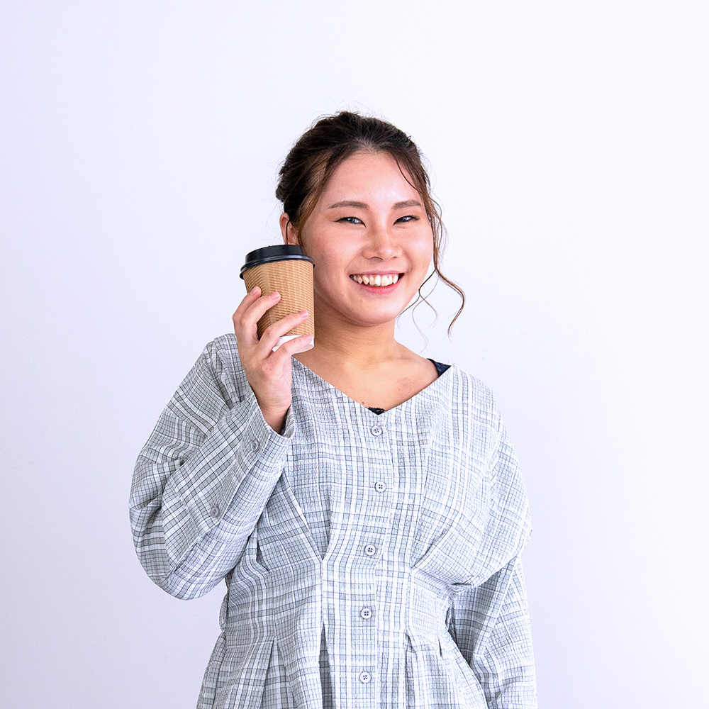 hasechiがホットコーヒーカップをほほにつけて笑っている写真