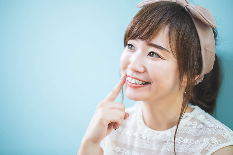 ほほを指さす女性
