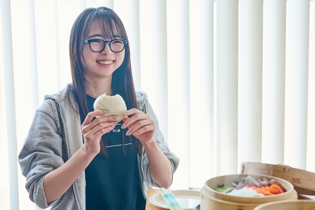 「ほかほかの料理から、ほんのり木の香りがすると癒やされます」と肉まんを頬張るりよ子さん